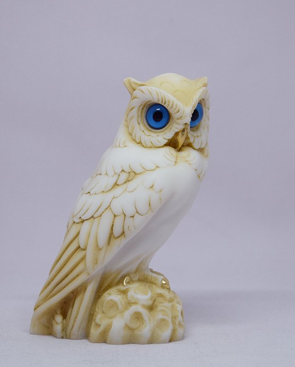 Owl observes statue sitting on a tree branch — image 2